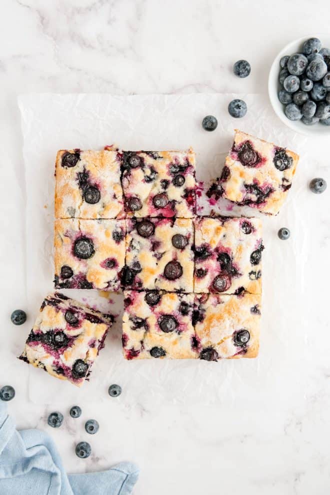 blueberry breakfast cake cut into nine slices on a piece of white parchment paper