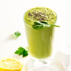 green detox smoothie in a glass cup with chia seeds sprinkled on top