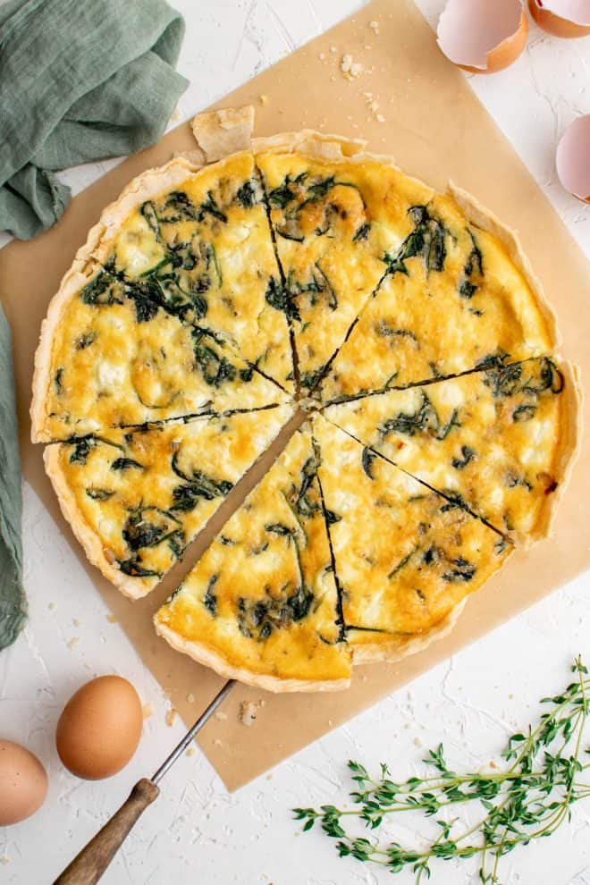 a spinach and feta quiche cut into 8 slices on a white table