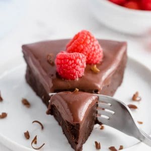 a fork taking a bite out of a slice of flourless chocolate cake