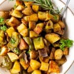 baked breakfast potatoes in a white bowl with a large spoon
