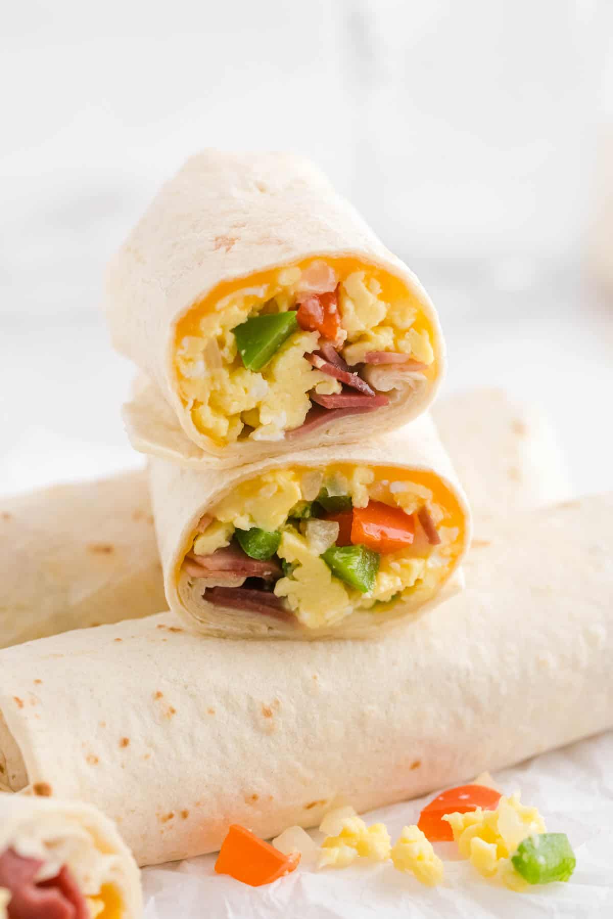 a cut breakfast burrito sitting on top of two rolled burritos