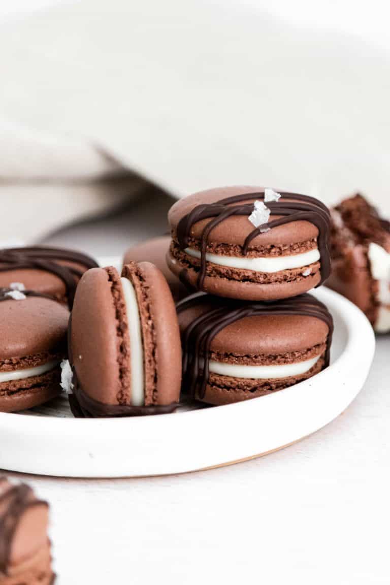 a stack of chocolate macarons sitting on a white plate
