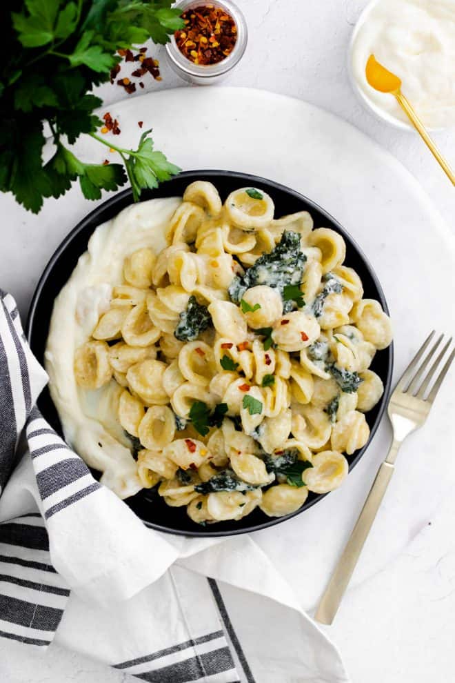 a plate with whipped ricotta and pasta with kale