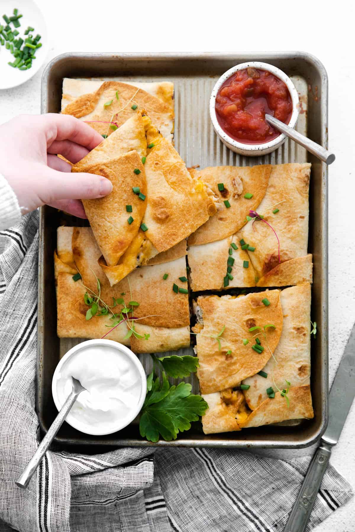 sheet pan quesadillas on a pan with sour cream and salsa