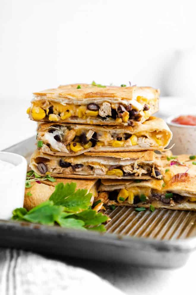 a stack of four pieces of sheet pan quesadillas sitting on a pan
