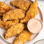 a plate of baked coconut chicken tenders with dip