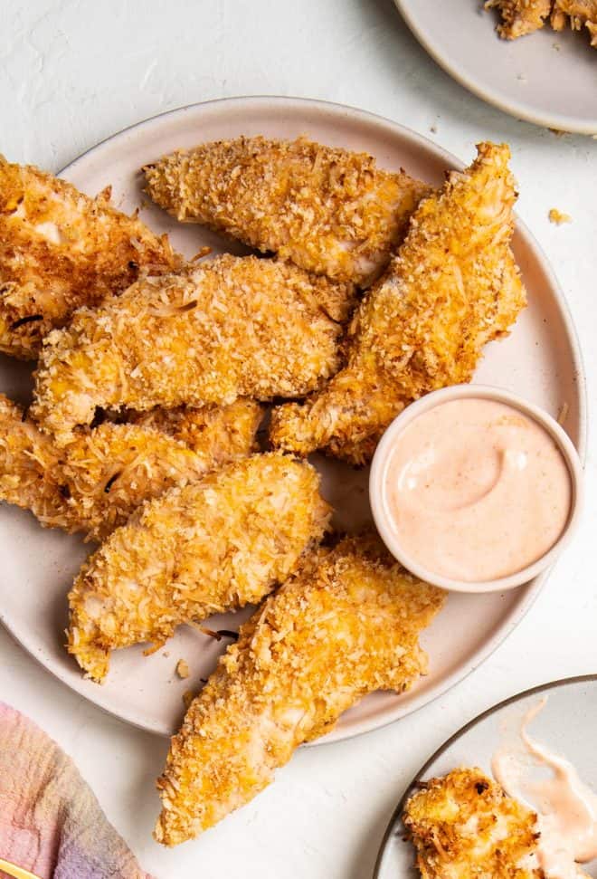 a plate of baked coconut chicken tenders with dip