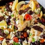 a piece of mediterranean chicken in a skillet with toppings