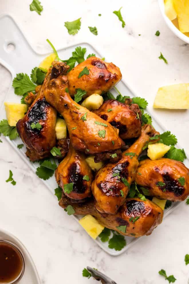 Hawaiian BBQ chicken wings garnished with chunks of pineapple and mint leaves.
