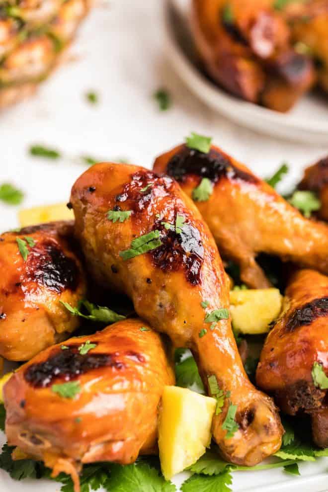A close-up of severa BBQ chicken wings on mint and pineapple.