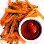 air fryer carrots sitting on a plate with a side of ketchup