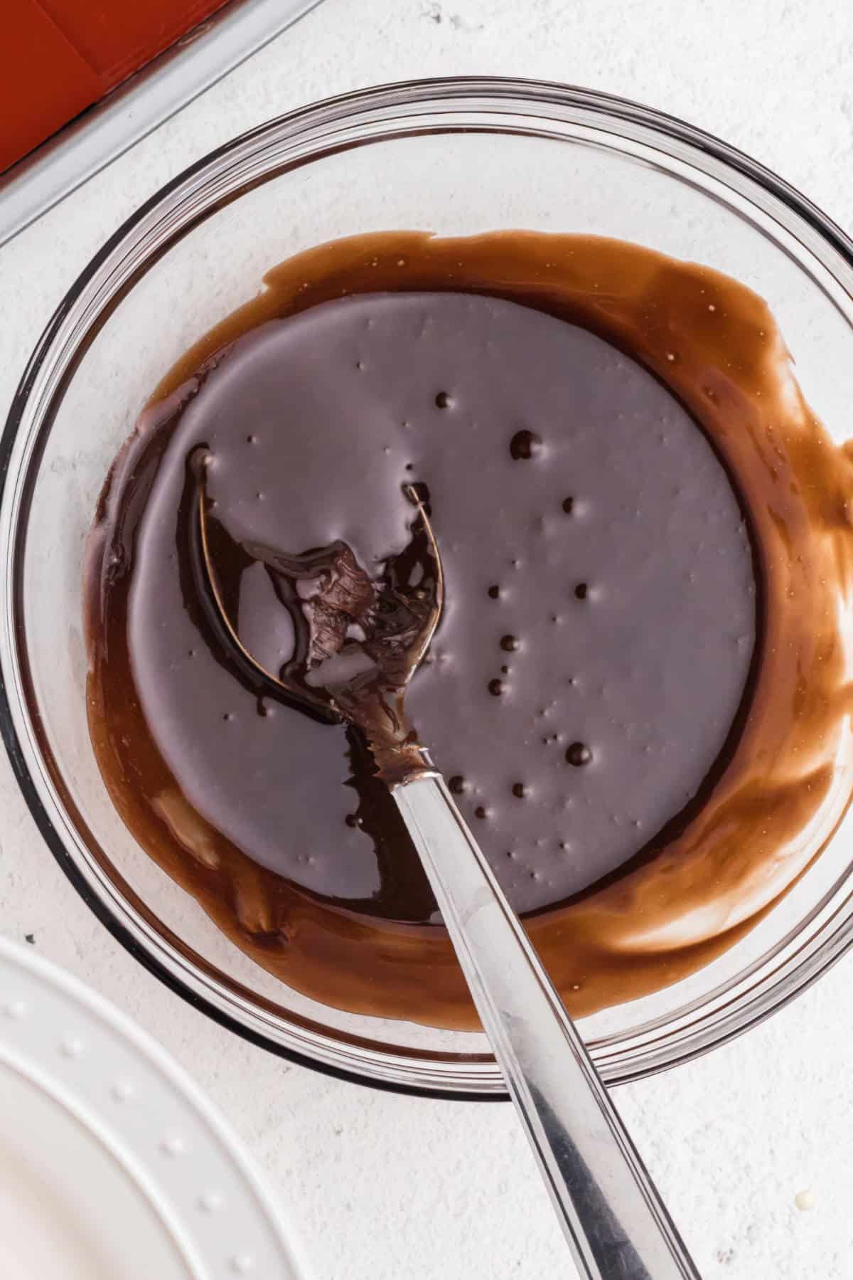 Smooth chocolate glaze made with melted chocolate and butter, stirred until glossy for topping eclairs.