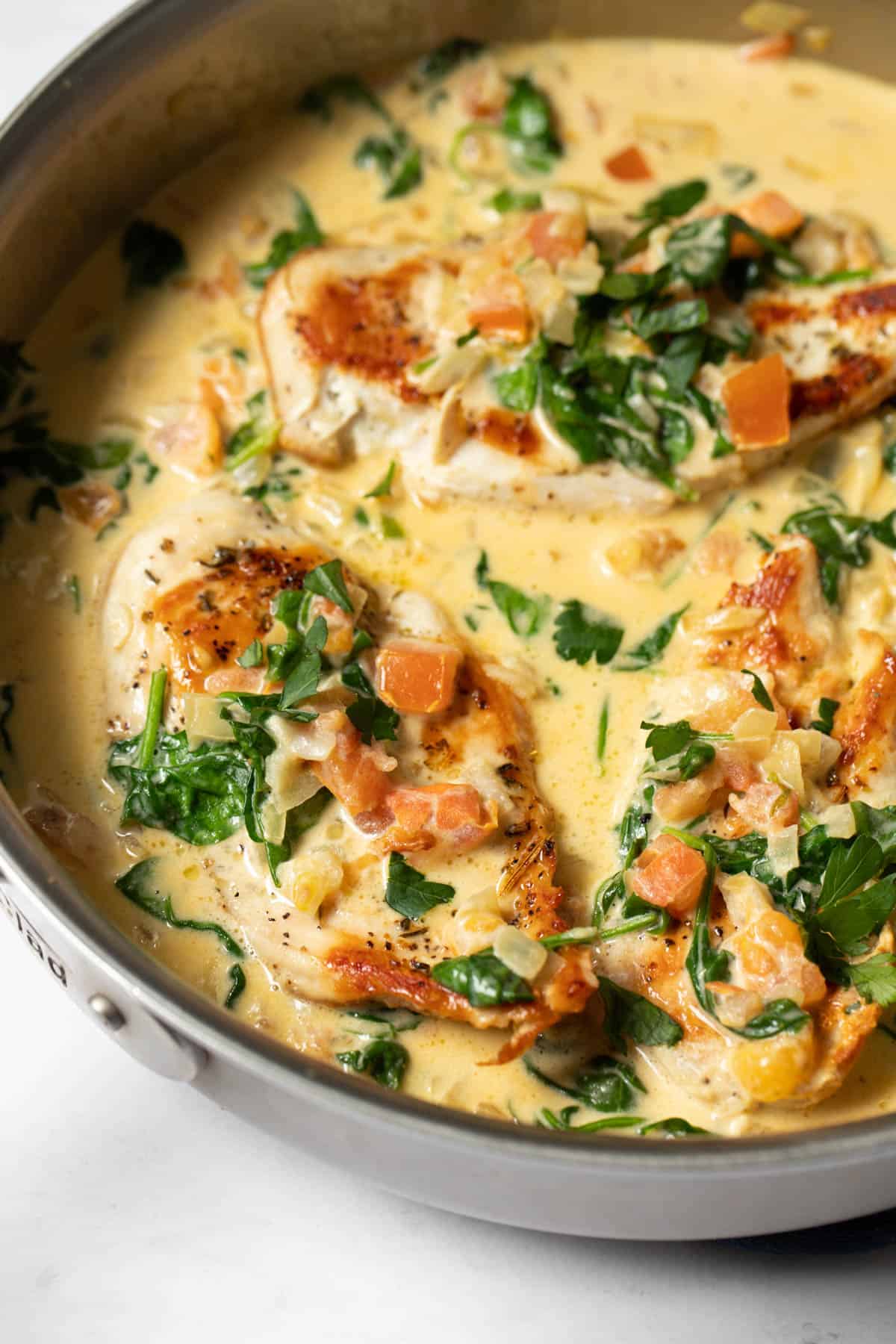 close up of chicken with tuscan garlic cream sauce in a skillet