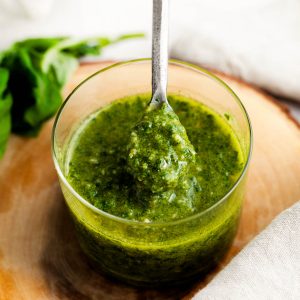 Homemade pesto sauce in a glass jar with a spoon