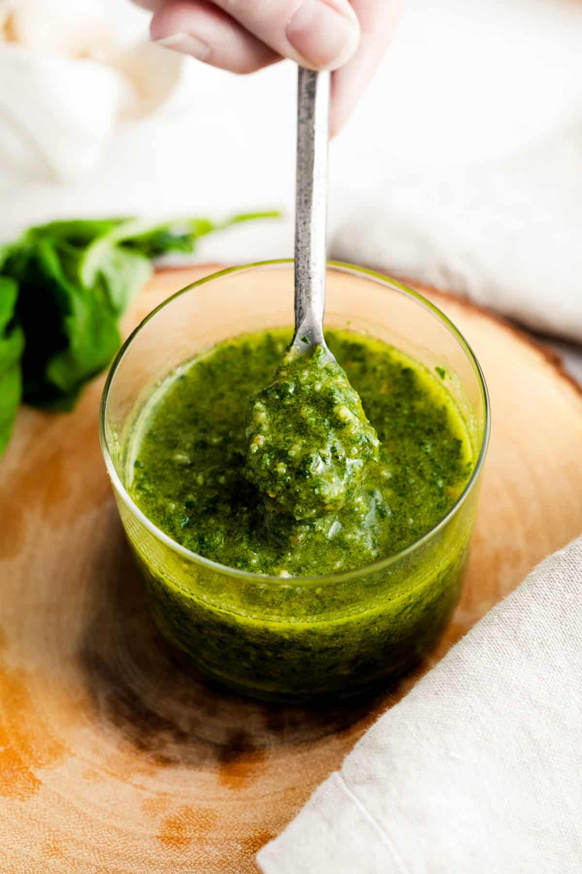 Homemade pesto sauce in a glass jar with a spoon