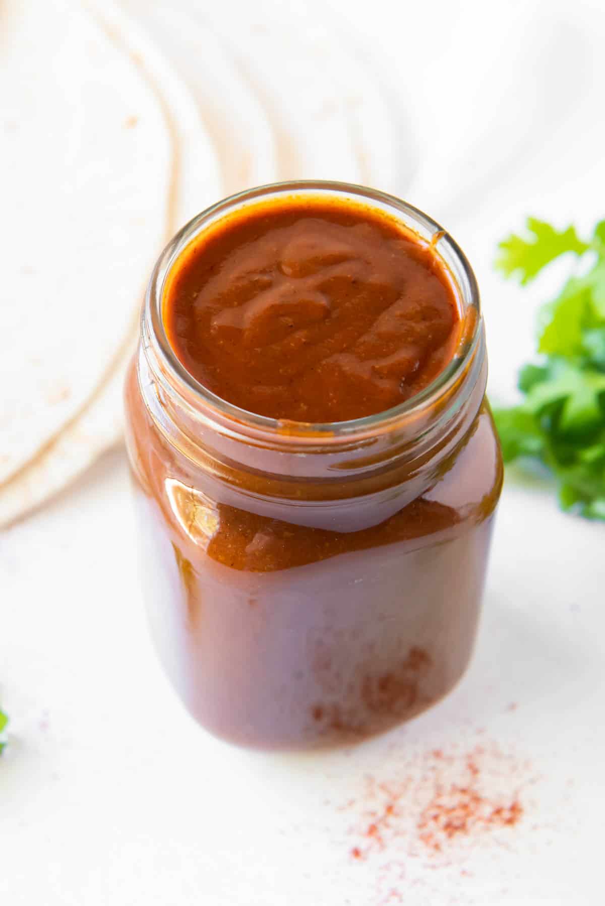 A glass jar filled with homemade enchilada sauce.