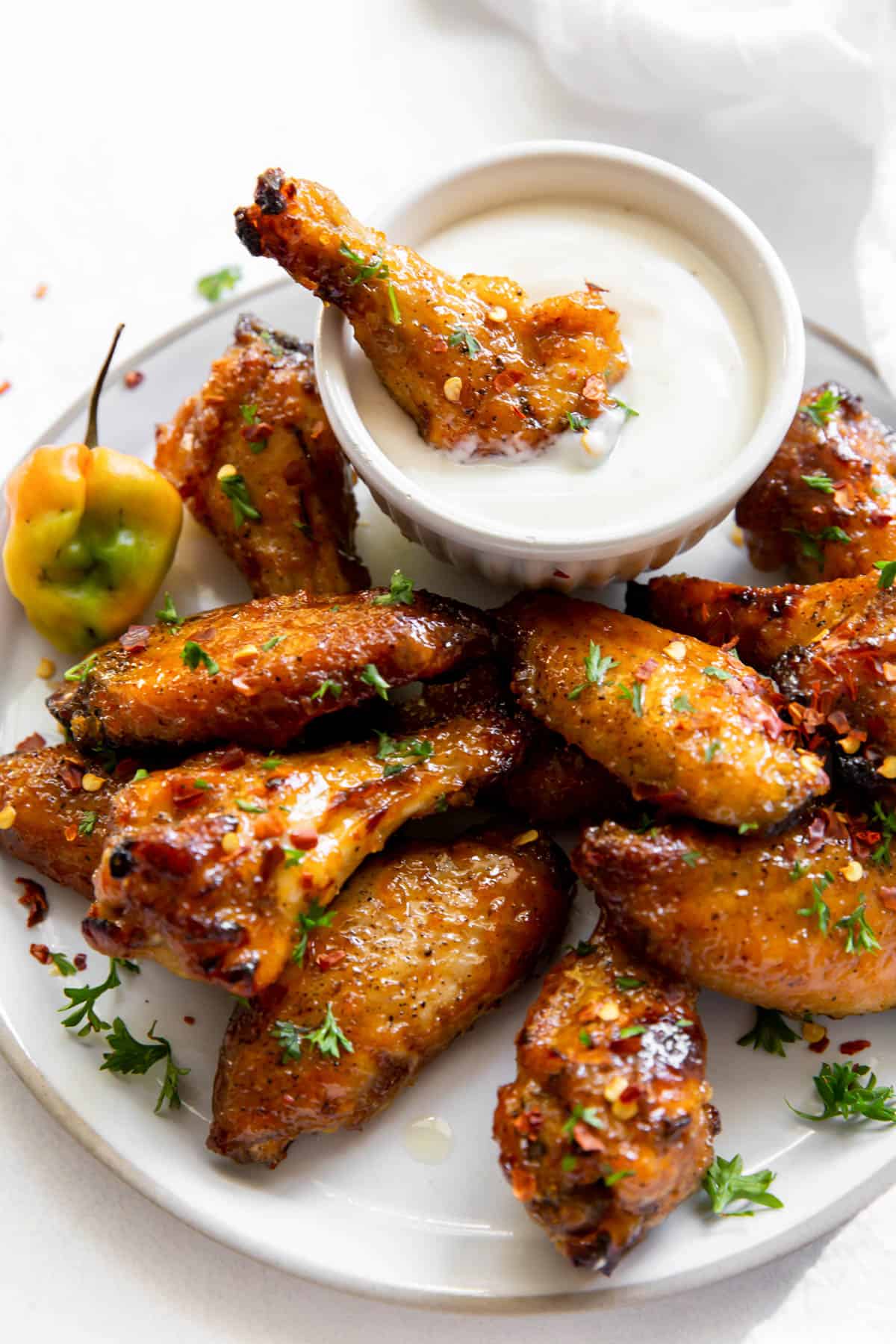 A plate of mango habanero chicken wings with one dipped in a cup of blue cheese