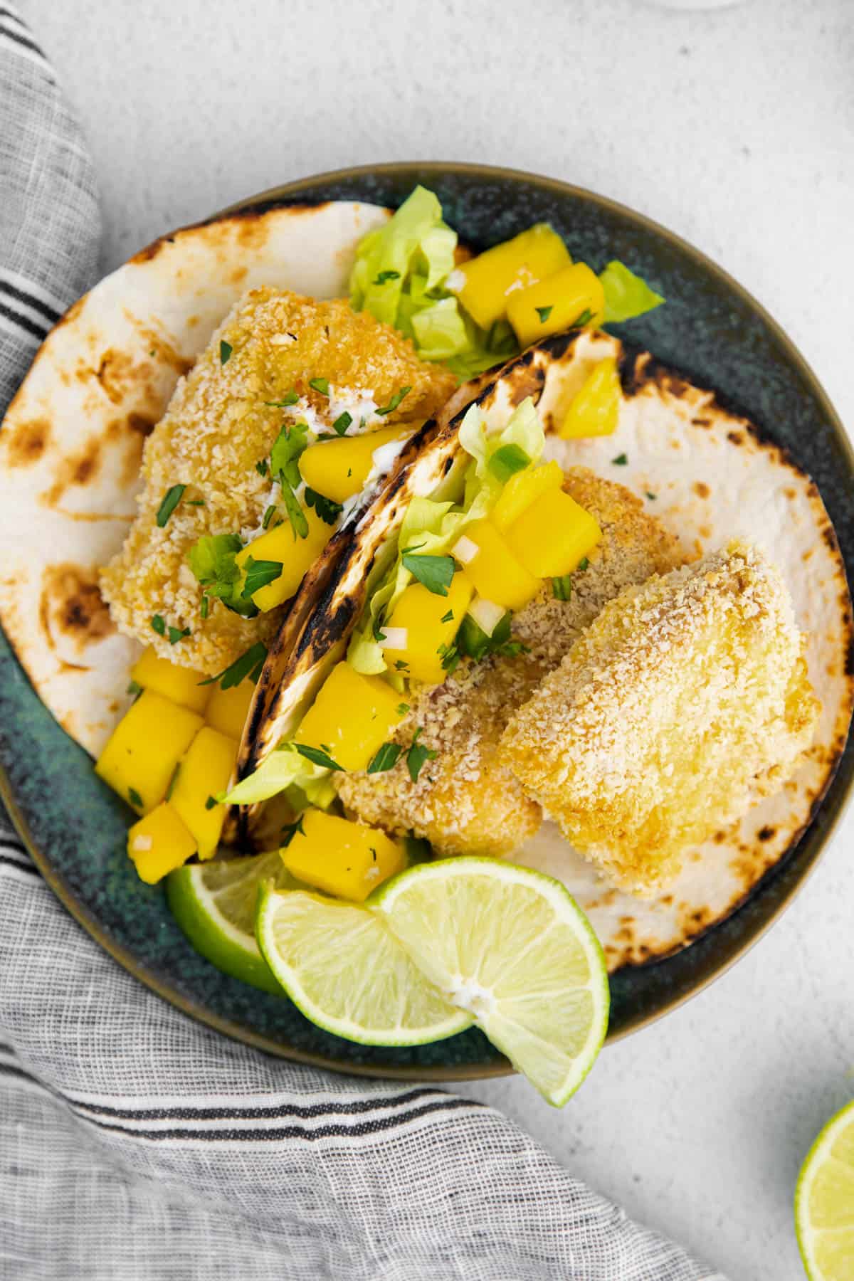 two mahi mahi fish tacos on a plate with mango salsa