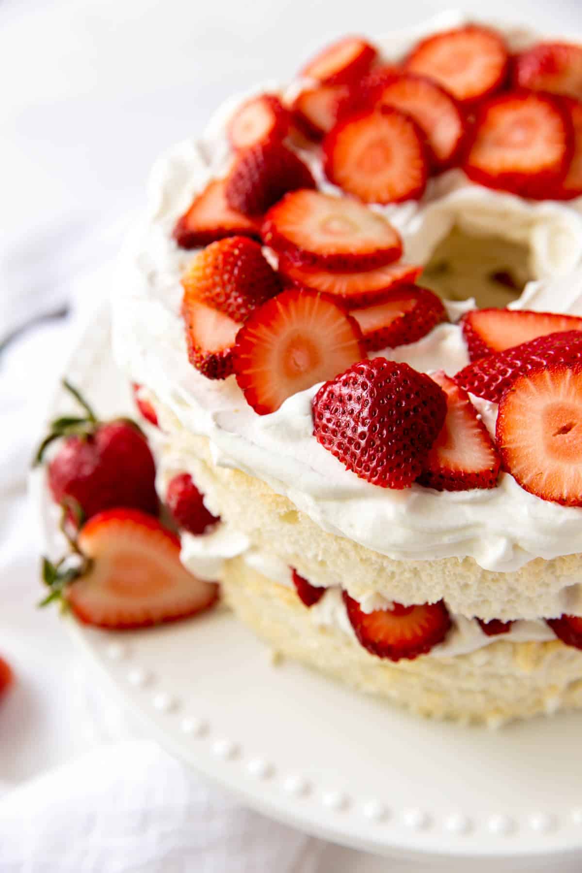 Angel food layer cake topped with strawberries and whipped cream