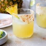 mezcal margarita in a glass with a salted rim and pineapple slice