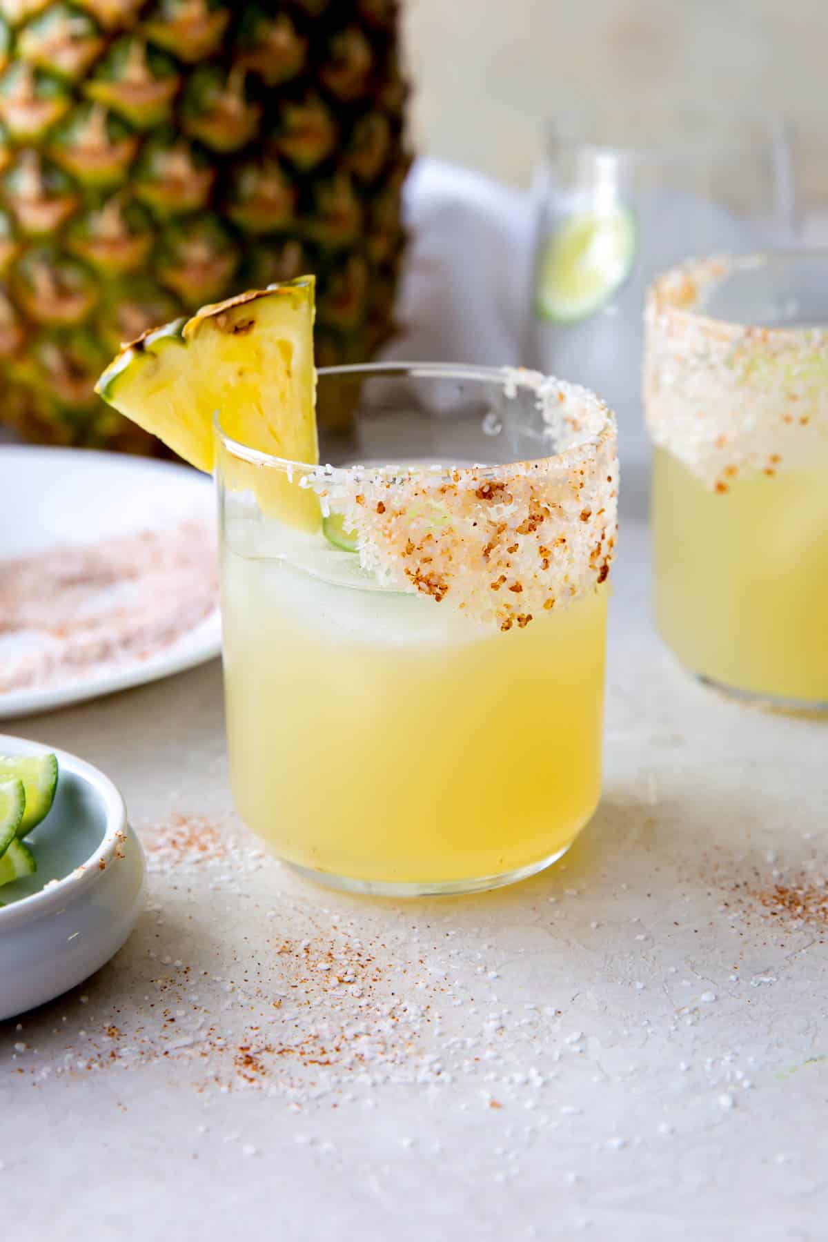 mezcal margarita in a glass with a salted rim and pineapple slice