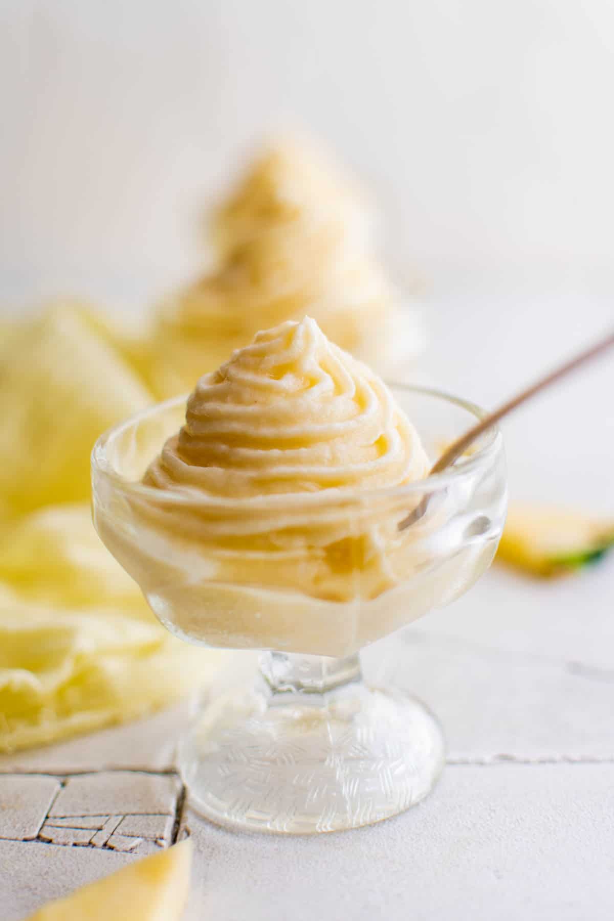 swirl of pineapple dole whip in a glass with a spoon