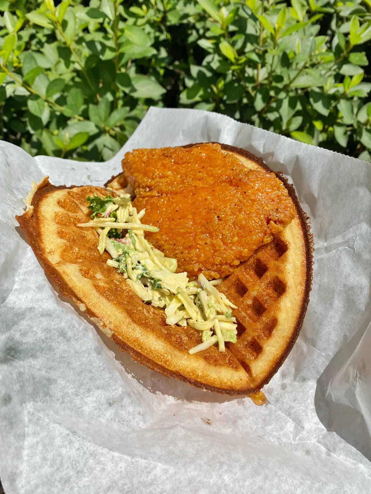 one waffle with coleslaw and fried chicken on top