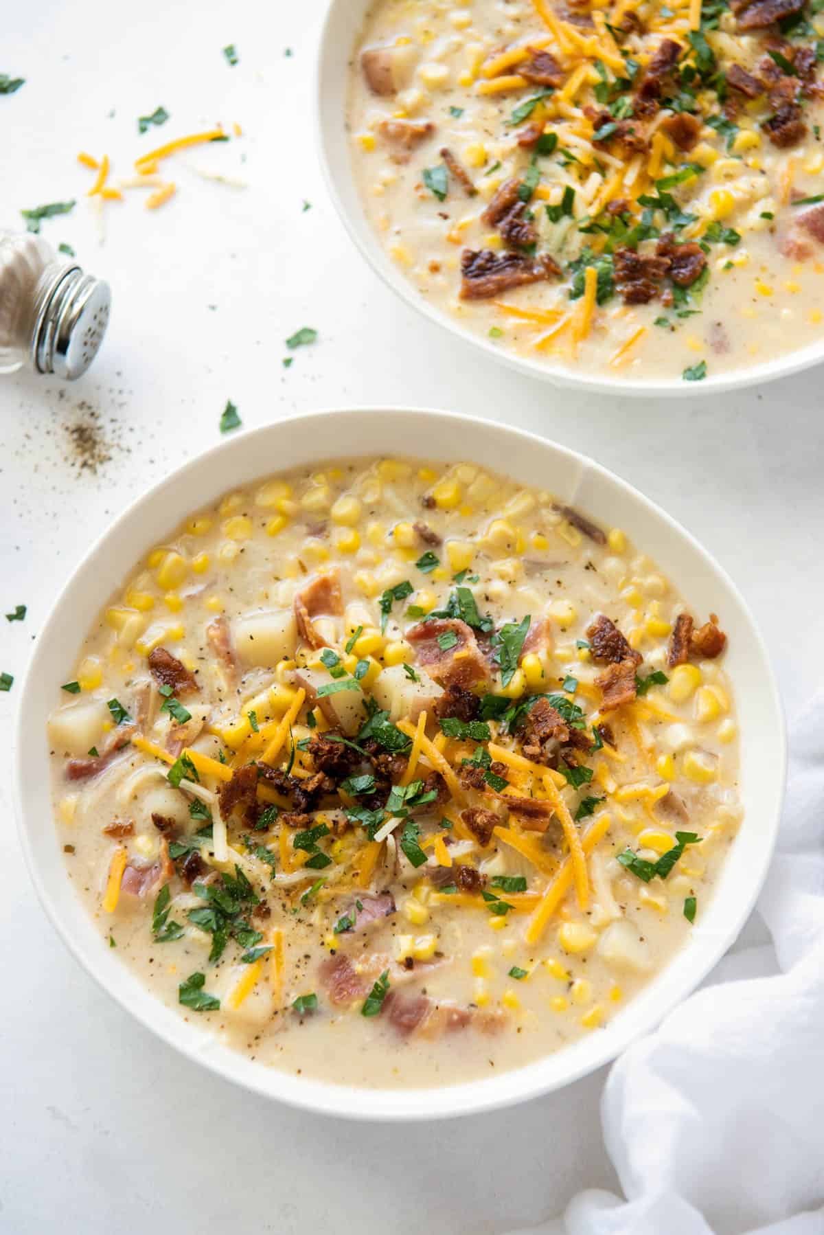 two bowls of corn chowder on a white table