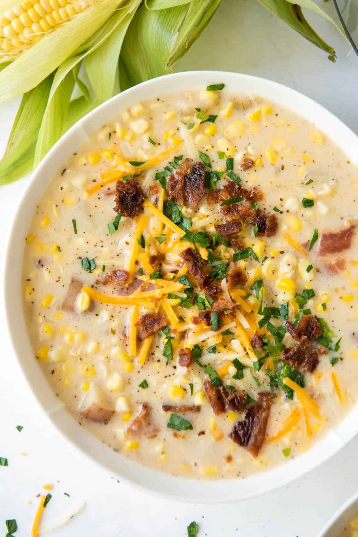 corn chowder in a bowl topped with bacon and cheddar cheese