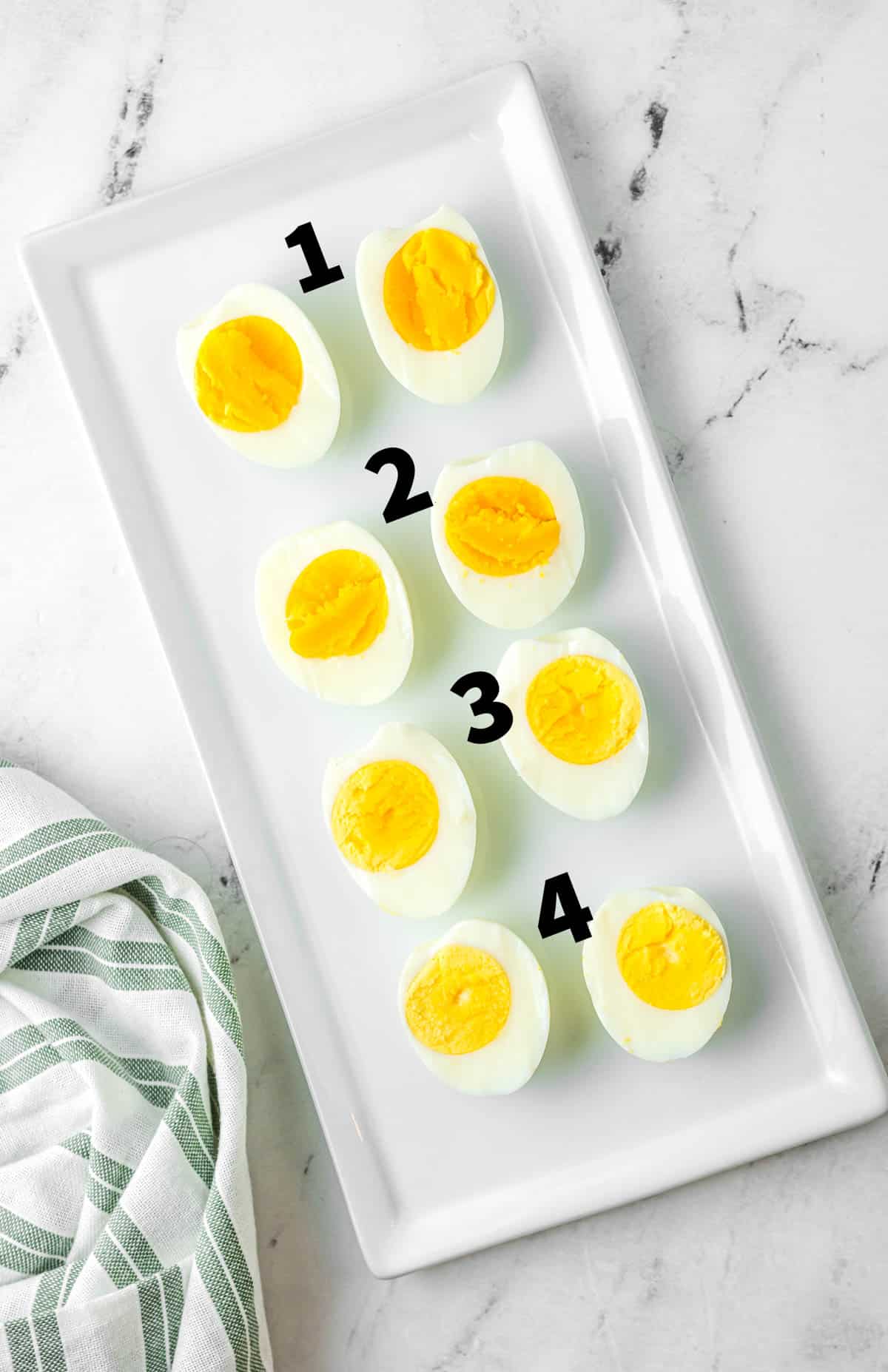 four hard boiled eggs sliced with different levels of doneness