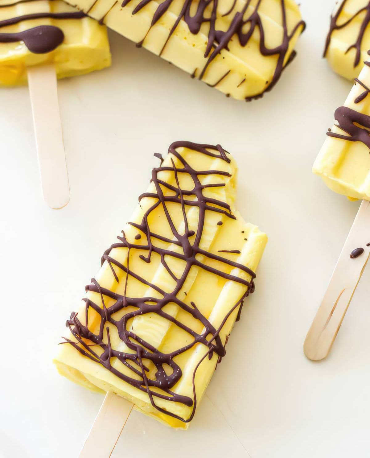 creamy mango popsicles drizzled with dark chocolate