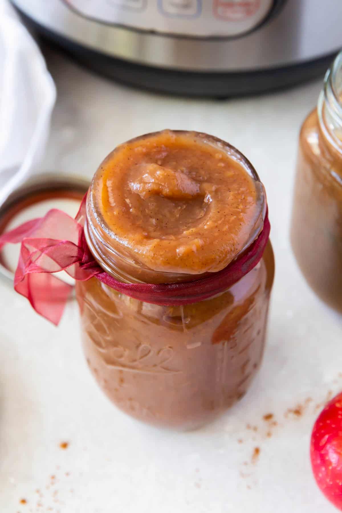 a glass jar filled with apple butter sitting on a countertop