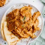 one plate of indian butter chicken with naan bread over rice