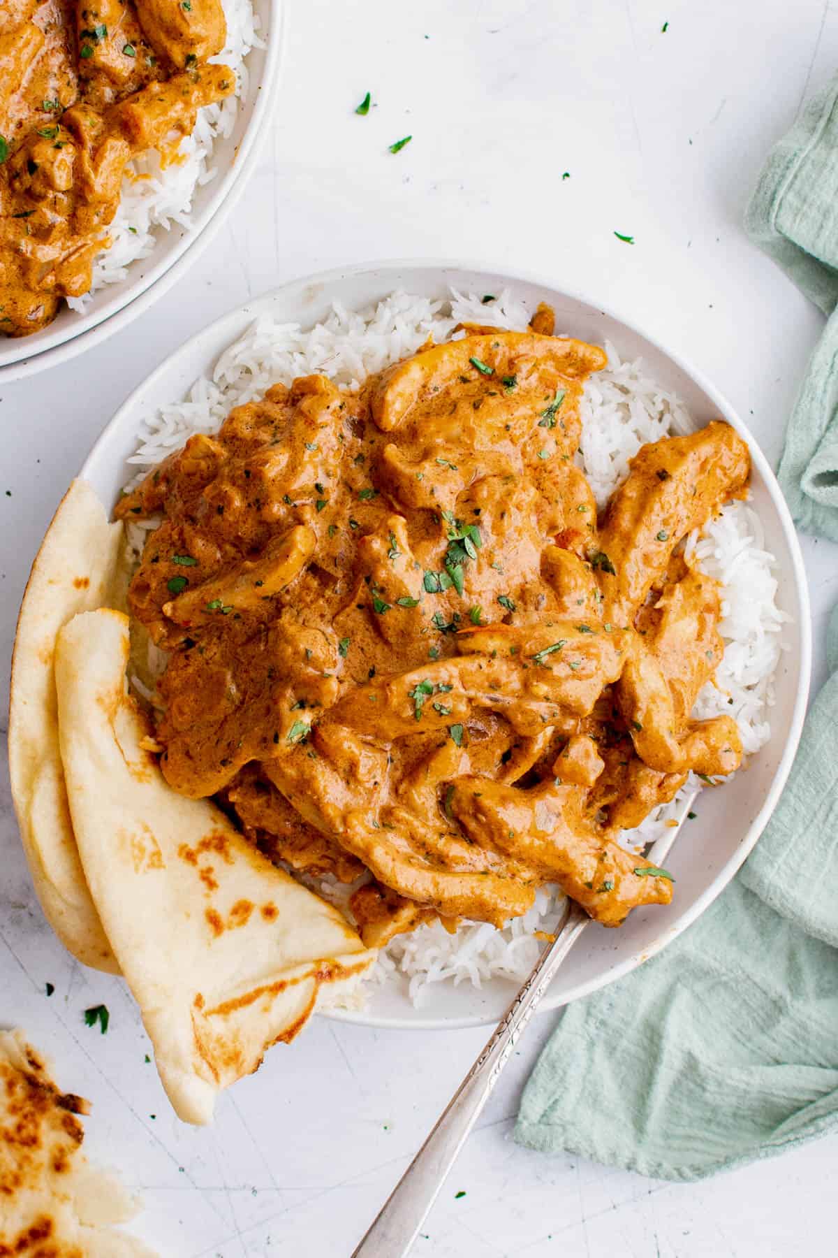 one plate of indian butter chicken with naan bread over rice