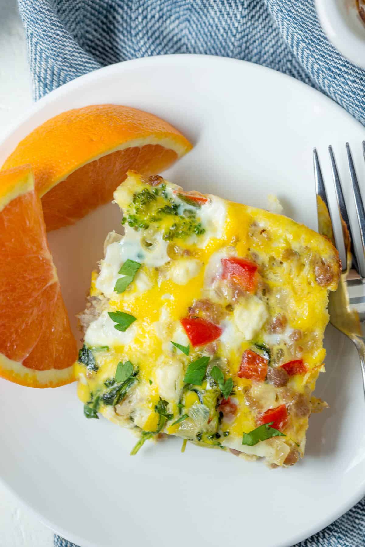 one slice of sausage egg bake on a plate with orange slices