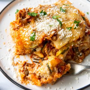 a slice of zucchini lasagna on a plate with a bite taken out with a fork