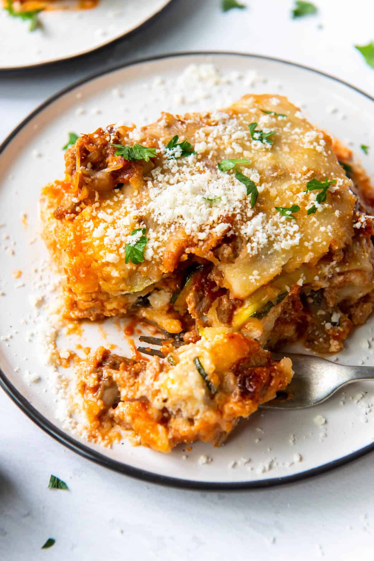 a slice of zucchini lasagna on a plate with a bite taken out with a fork