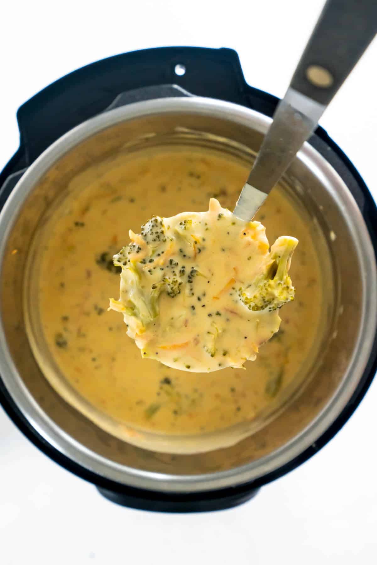 a soup ladle filled with broccoli cheese soup over an instant pot bowl