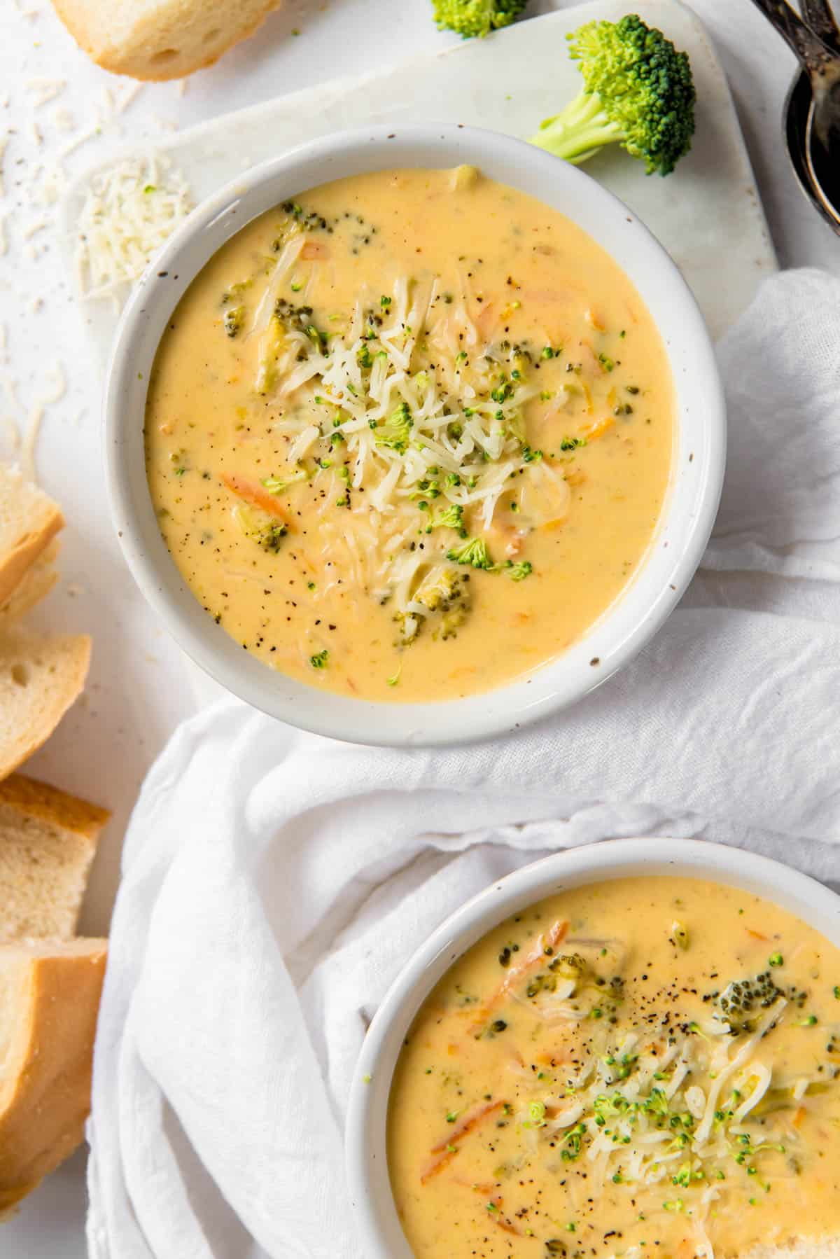 two bowls filled with broccoli cheddar soup with sprinkle of cheese on top
