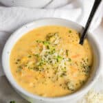 one bowl filled with instant pot broccoli cheddar soup with a spoon in it