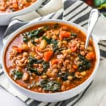 a bowl of lentil and kale sitting sitting on a tabletop