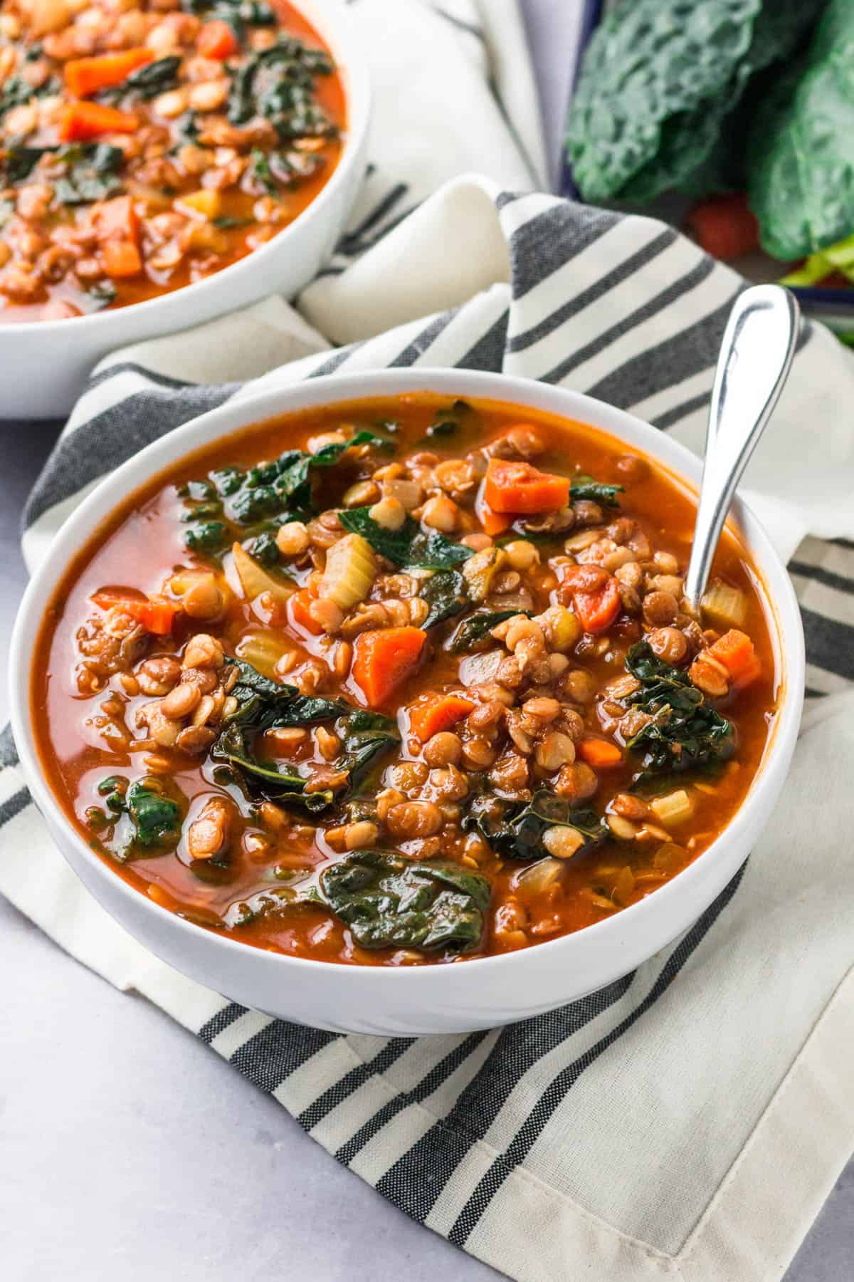 a bowl of lentil and kale sitting sitting on a tabletop