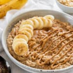 a bowl of peanut butter banana oatmeal with peanut butter sauce drizzled on top