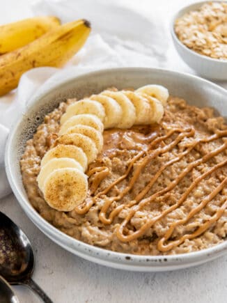 a bowl of peanut butter banana oatmeal with peanut butter sauce drizzled on top