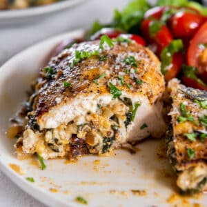 spinach ricotta stuffed chicken cut in half on a plate