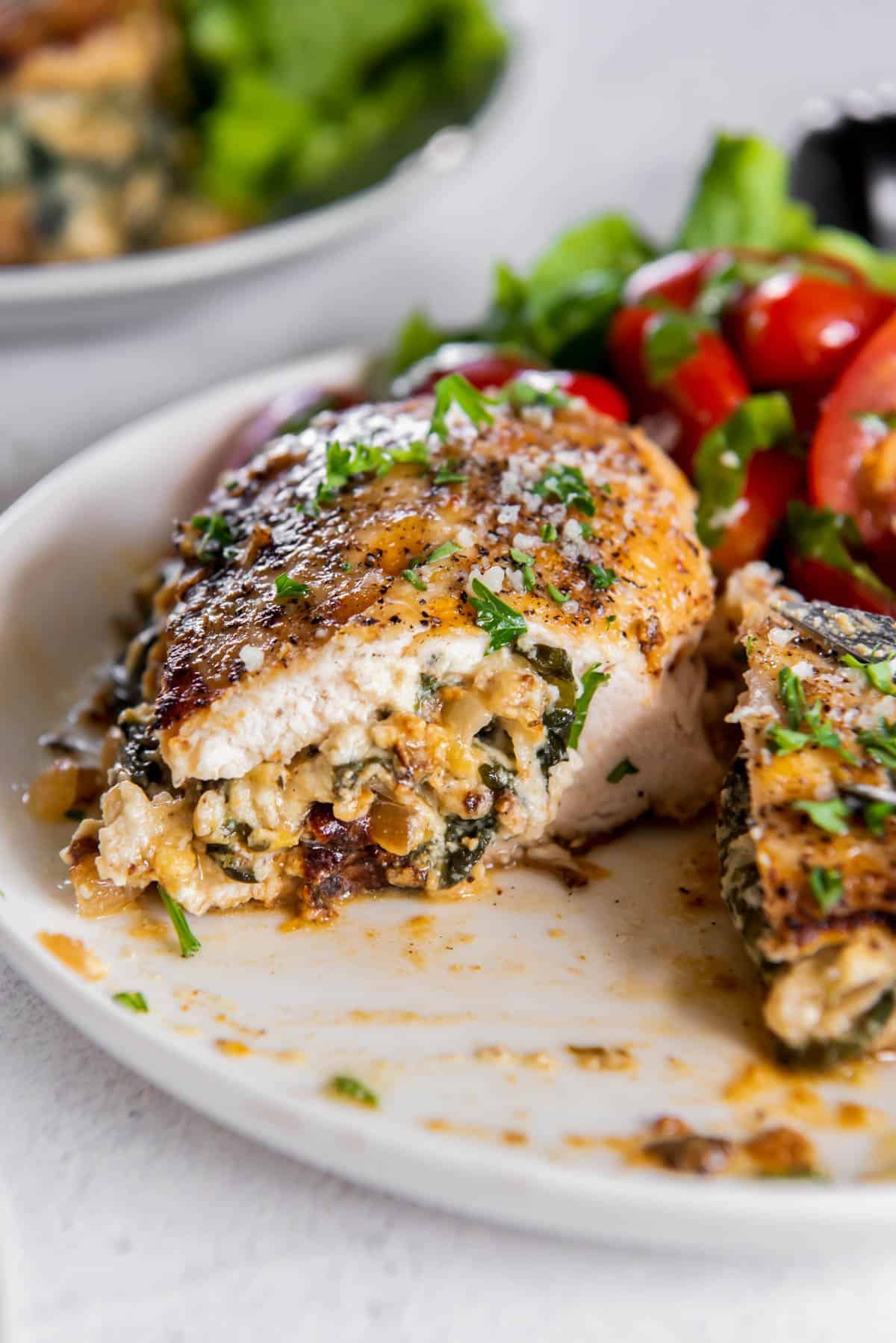 spinach ricotta stuffed chicken cut in half on a plate