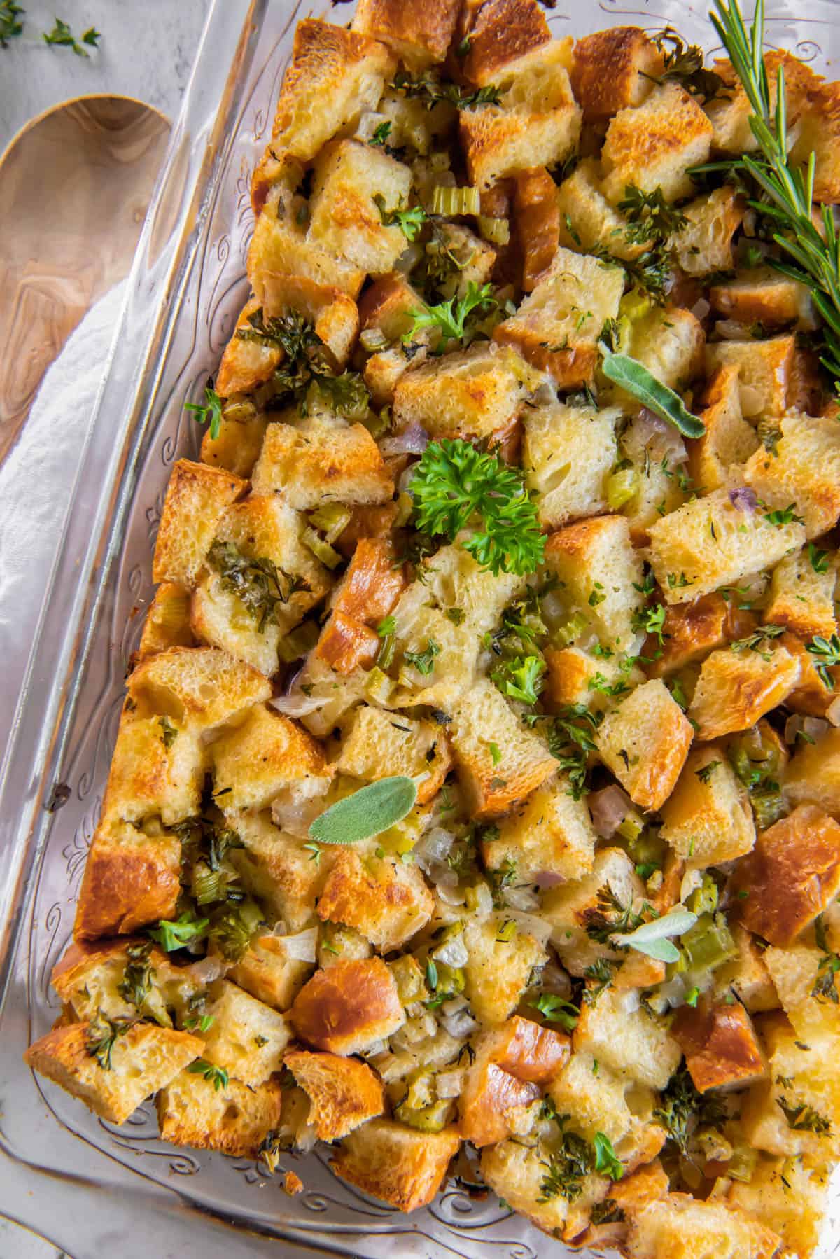 thanksgiving stuffing in a casserole dish with fresh herbs on top
