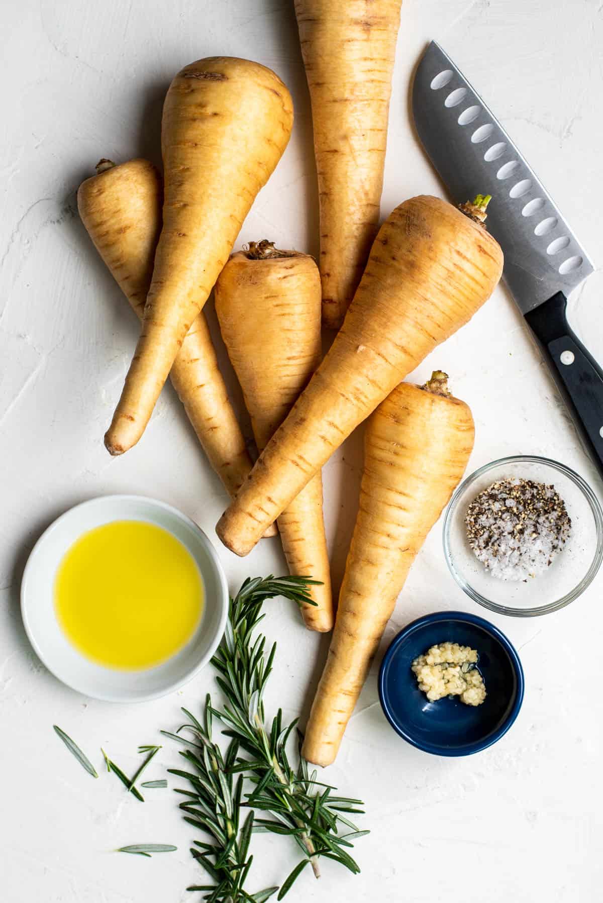 all of the ingredients for roasted parsnips on a white countertop