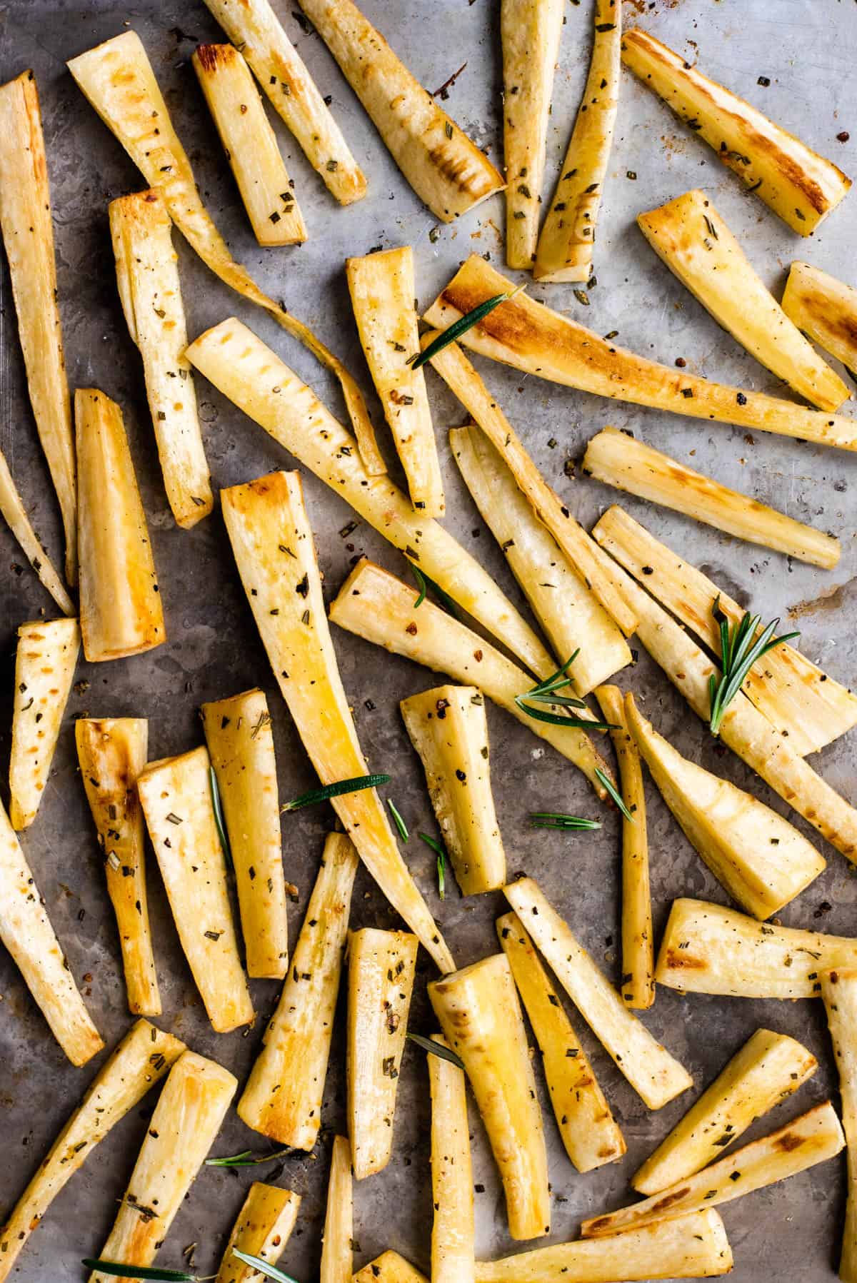 roasted parsnips on a baking sheet with rosemary